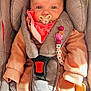baby, infant, pacifier, car_seat, child, pink_clothing, bead_chain, sitting, face, blue_eyes, soft_toys, childrens_accessories, cute, indoor, portrait, baby_clothes, comfort, young_child, seat_belt, warm_clothing