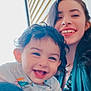 child, toddler, woman, smile, happy, indoor, portrait, curly_hair, long_hair, floral_clothing, casual, family, love, joy, person, face, window, light, candid, together