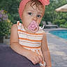 blue_eyes, blurred_background, child, cushion, cute, daylight, garden, hair, hand, headband, outdoor, pacifier, pink, poolside, portrait, relaxing, skin, striped_dress, summer, toddler