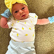 Angelina joined the competition — help win amazing prizes! baby, infant, yellow_bow, mittens, lemon_pattern, white_shirt, blue_pants, carpet, lying_down, cute, portrait, face, headband, clothing, child, soft_texture, indoor, young, person, newborn
