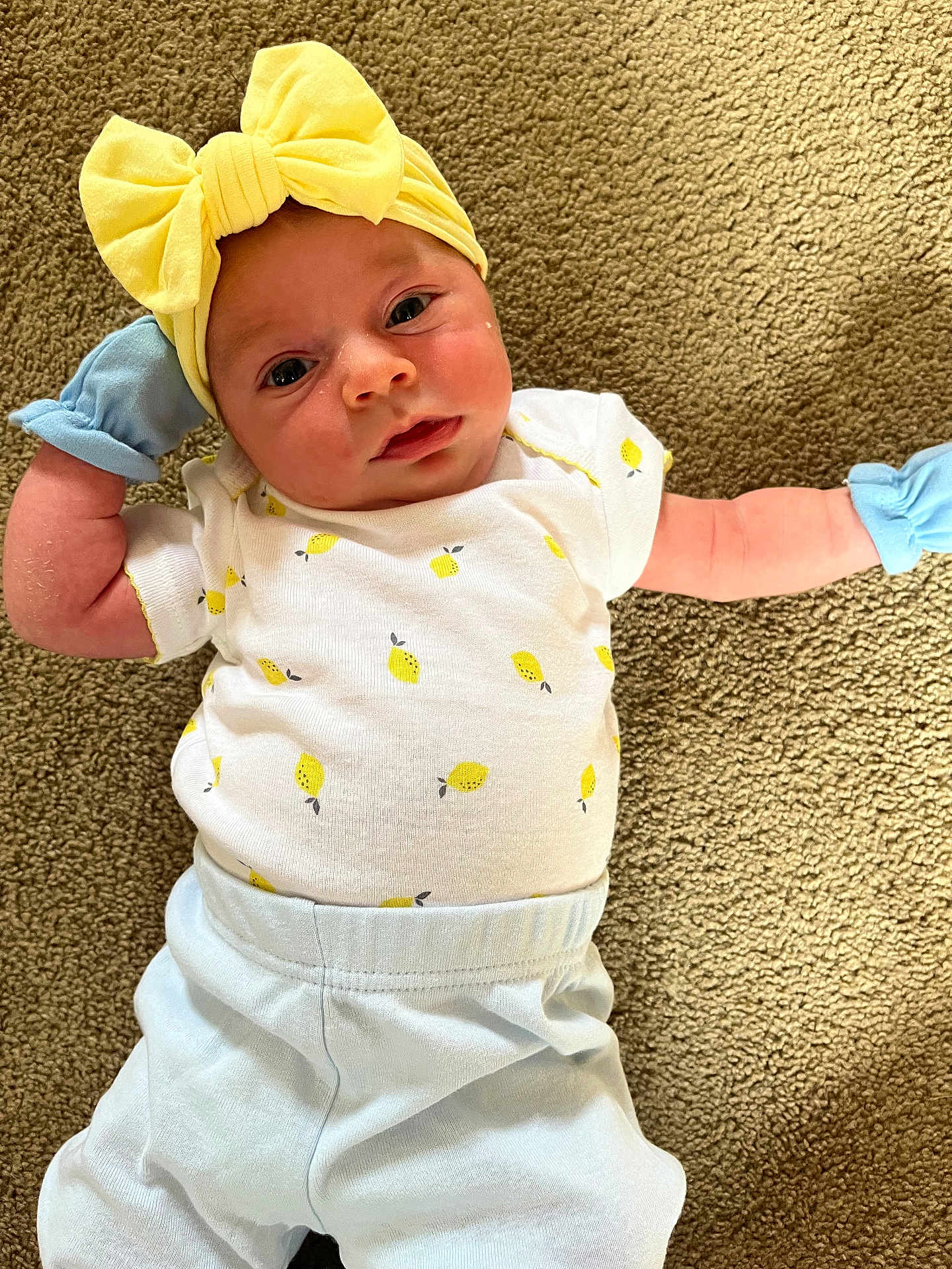 Angelina joined the competition — help win amazing prizes! baby, infant, yellow_bow, mittens, lemon_pattern, white_shirt, blue_pants, carpet, lying_down, cute, portrait, face, headband, clothing, child, soft_texture, indoor, young, person, newborn