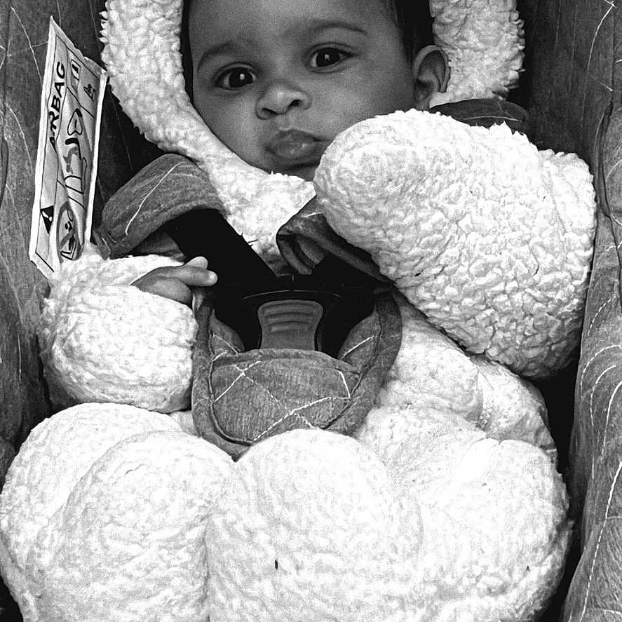 Kayden a rejoint le concours — aidez-le/la à gagner de superbes lots ! baby, child, car_seat, costume, fluffy, black_and_white, cute, infant, portrait, face, clothing, straps, seat, young_child, warm, winter_wear, expression, indoors, safety, adorable
