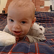 Eliott participe au concours pour gagner de l'argent avec cette photo : baby, infant, plaid_blanket, bed, smile, face, indoor, young_child, cute, eyes, person, child, cozy, soft_lighting, blanket, home, portrait, clothing, head, baby_gesture