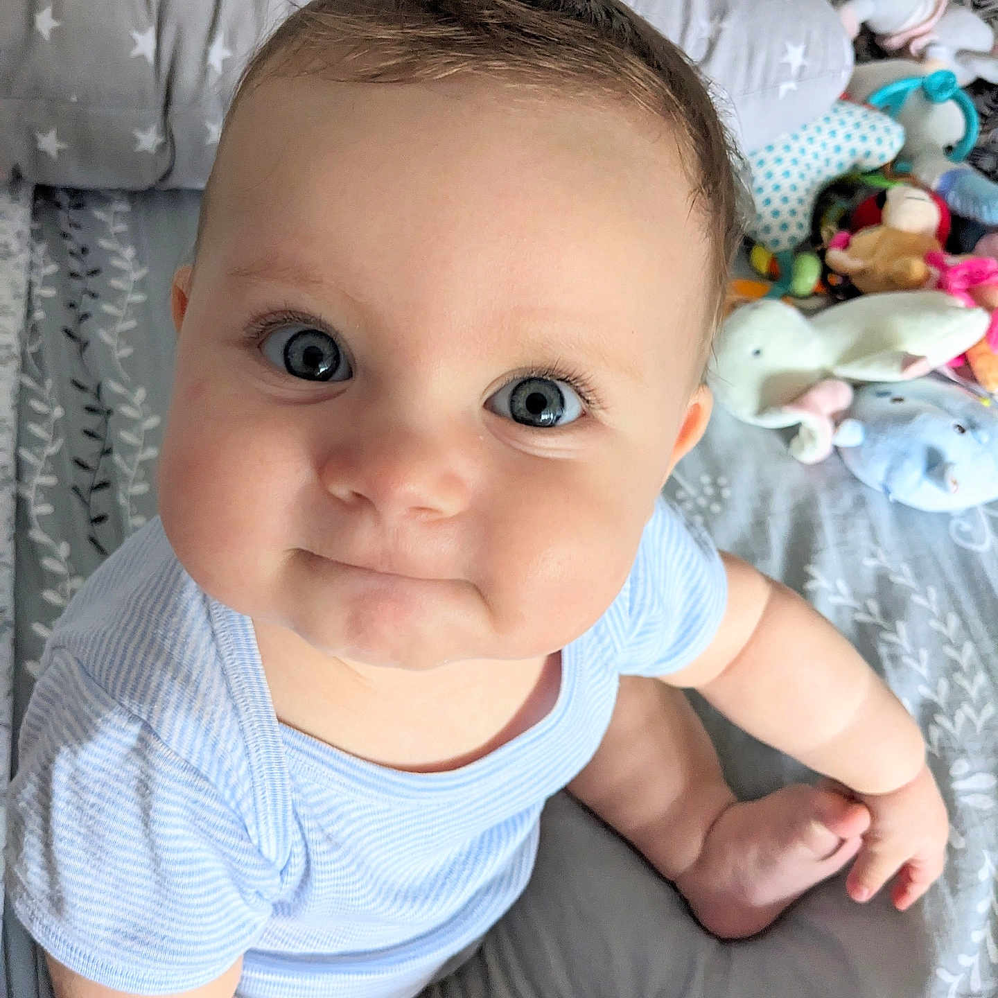 Mya Luna a rejoint le concours — aidez-le/la à gagner de superbes lots ! baby, child, blue_eyes, chubby_cheeks, infant, plush_toys, bed, pillow, clothing, onesie, cute, indoor, person, portrait, smile, sitting, young_child, soft_toys, nursery, playtime