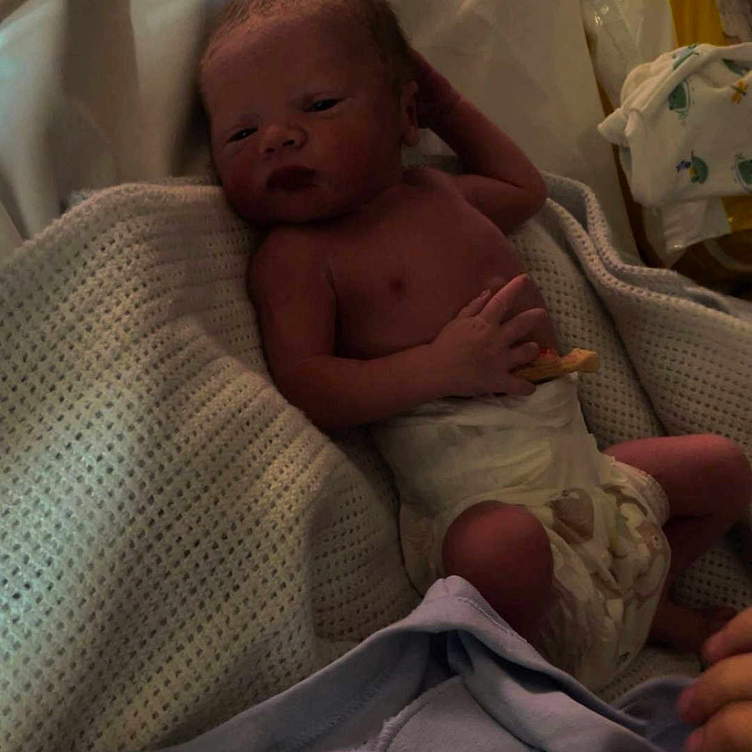 John-Peter joined the competition — help win amazing prizes! baby, bassinet, bed, blanket, clothing, cozy, diaper, eyes_open, face, hand, infant, newborn, nursery, parent_hand, portrait, resting, skin, snapchat_logo, soft_lighting, swaddle