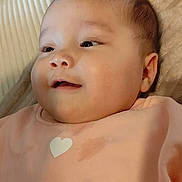 Constance a rejoint le concours — aidez-le/la à gagner de superbes lots ! baby, infant, child, smiling, portrait, closeup, face, onesie, heart_print, bedding, blanket, cheeks, eyelashes, ear, skin, lying_down, happy, soft_texture, stain, candid