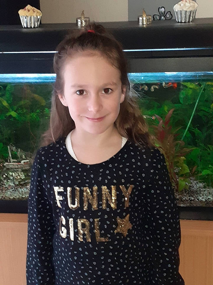 Eloane participe au concours pour gagner de l'argent avec cette photo : blond, brown_hair, child, cool, display_device, fish, fun, happy, iris, joy, long_hair, organ, pattern, person, plant, room, sleeve, smile, standing, t_shirt