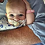baby, pacifier, hospital_wristband, arm, adult, clothing, person, holding, closeup, face, skin, hospital_gown, blue, pink, infant, child, care, comfort, expression, portrait