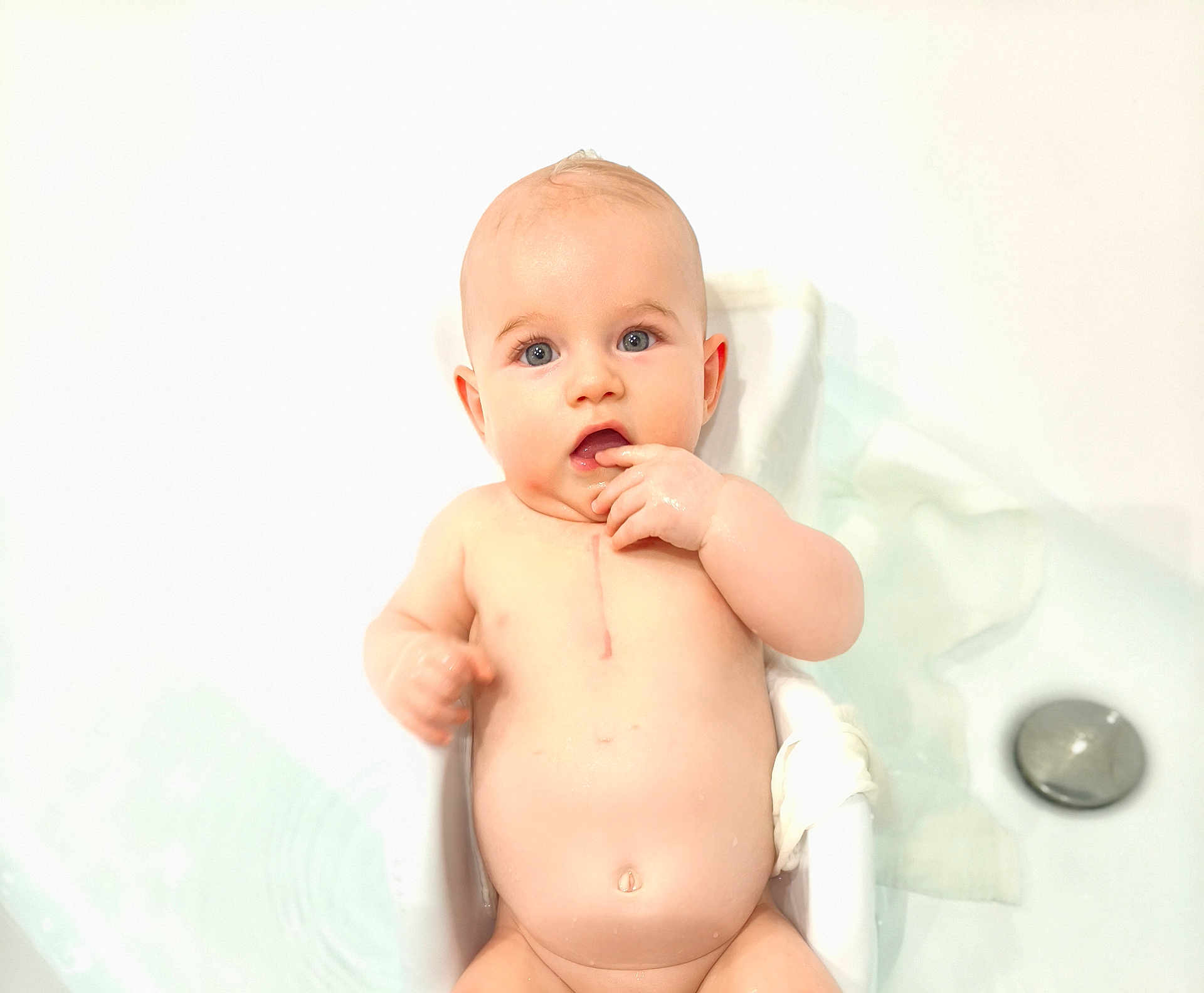 Martin participe au concours pour gagner de l'argent avec cette photo : baby, infant, bathtub, water, naked, skin, blue_eyes, hand, finger_in_mouth, bathroom, white_background, curious, child, cute, sitting, plump, clean, soft_light, portrait, young