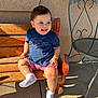 toddler, child, smiling, bench, wood, outdoor, sunlight, shadow, wall, clothing, shorts, shirt, socks, happy, person, seat, metal_chair, texture, daylight, cute