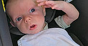 Callahan is registered to the contest to win money with this photo: baby, infant, child, car_seat, blanket, white_blanket, portrait, face, wide_eyes, surprised, salute, raised_hand, sitting, vehicle, travel, indoors, 安全, cozy, photography, cute