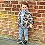 Feroze is registered to the contest to win money with this photo: child, boy, smiling, brick_wall, hoodie, camouflage_jacket, casual_clothing, sneakers, outdoor, standing, street, urban, happy, young_kid, fashion, playful, person, portrait, concrete, grin