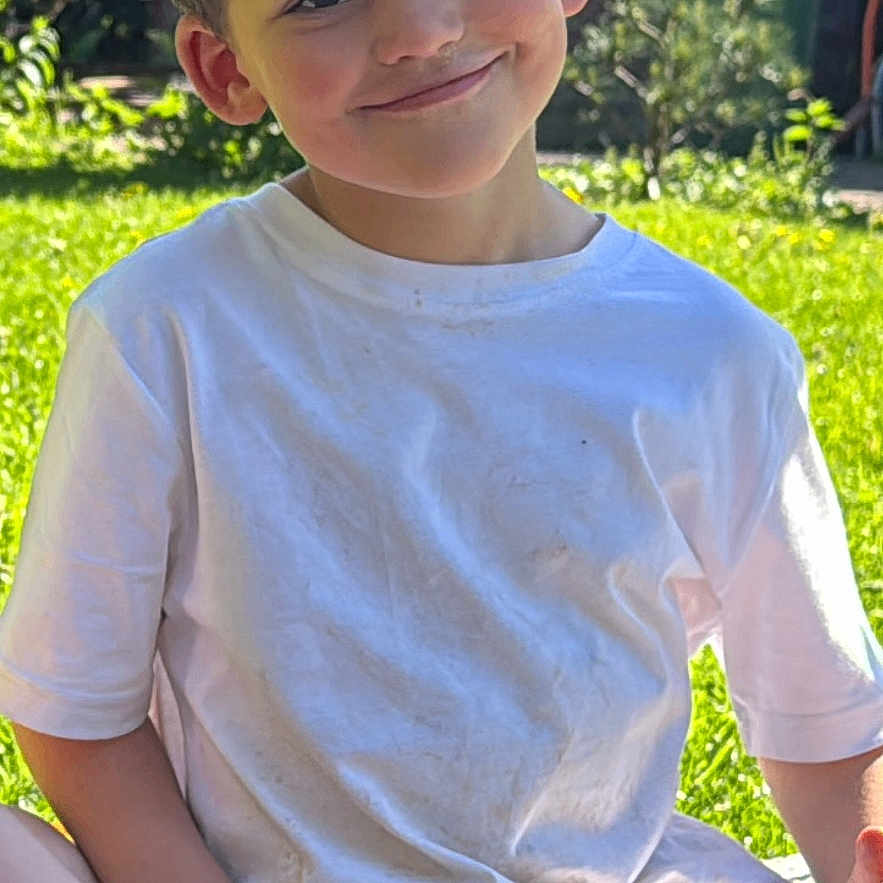 Feroze joined the competition — help win amazing prizes! boy, casual_clothing, child, curly_hair, daylight, garden, grass, greenery, happy, juice_box, nature, outdoor, playful, portrait, relaxed, sitting, smiling, snack, sunlight, white_tshirt