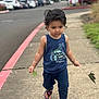 toddler, child, sidewalk, leaves, tank_top, pants, sandals, footwear, outdoor, walking, parking_lot, cars, grass, bracelet, hair, person, summer_clothing, nature, daytime, concrete