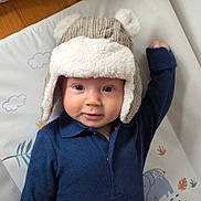 Rory joined the competition — help win amazing prizes! baby, child, hat, bear_hat, blue_shirt, play_mat, elephant, plants, raised_arm, smiling, face, indoor, cute, cozy, infant, portrait, person, headwear, expression, soft_texture