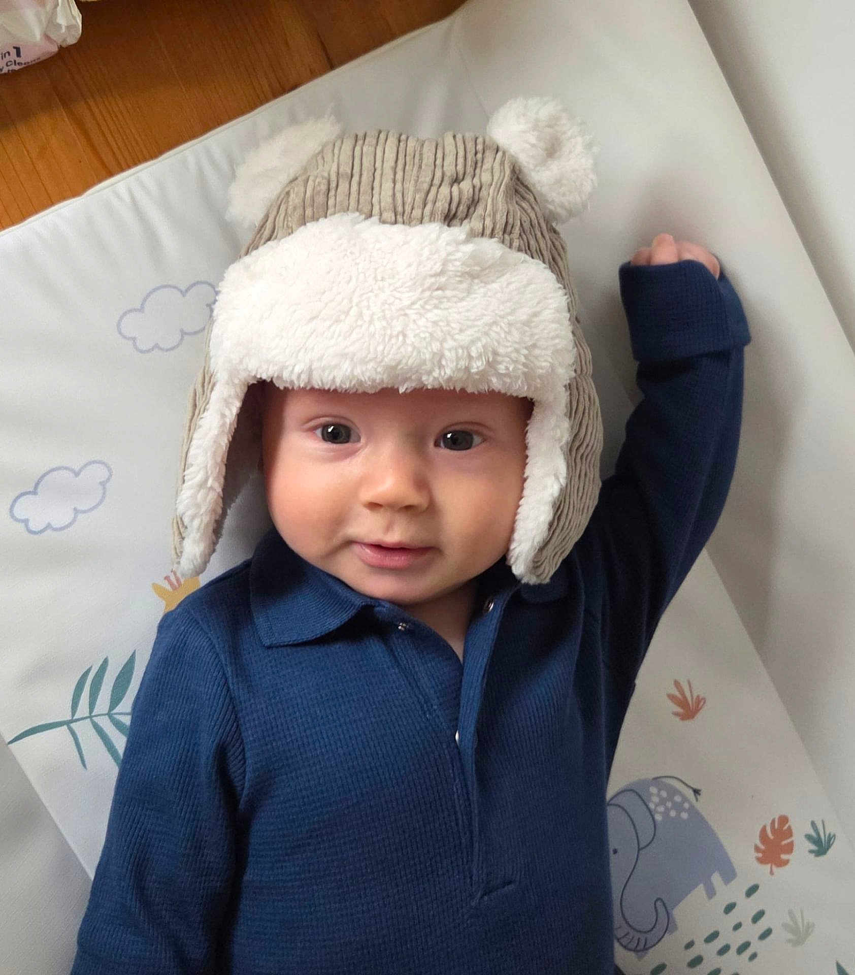 Rory joined the competition — help win amazing prizes! baby, child, hat, bear_hat, blue_shirt, play_mat, elephant, plants, raised_arm, smiling, face, indoor, cute, cozy, infant, portrait, person, headwear, expression, soft_texture
