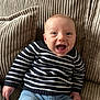 baby, smiling, happy, child, infant, striped_sweater, blue_jeans, couch, beige, textured, comfortable, portrait, indoor, cute, young_child, person, sitting, clothing, head, face