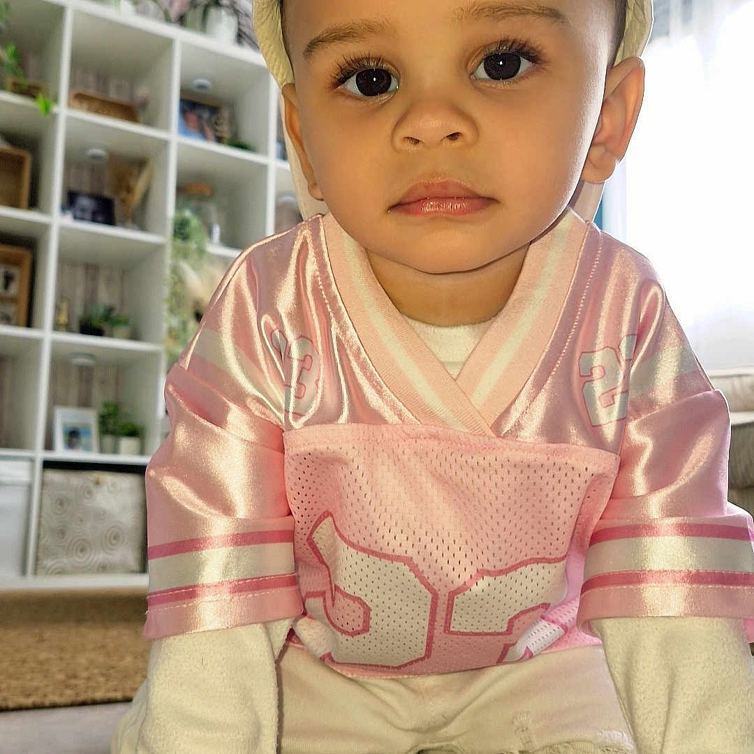Kahïl participe au concours pour gagner de l'argent avec cette photo : toddler, child, crawling, pink_jersey, cap, white_clothing, indoor, living_room, plants, shelf, decor, curious, portrait, young_child, floor, hands, eyes, casual, home, cute