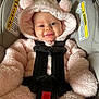 baby, infant, car_seat, pink, fluffy, hood, smiling, face, child, seatbelt, safety, cute, apparel, clothing, young_child, indoors, portrait, expression, happy, cozy