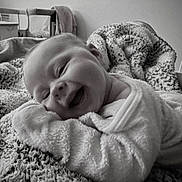 Willow is registered to the contest to win money with this photo: baby, black_and_white, blanket, child, content, cozy, cute, expression, face, fuzzy, happy, indoor, infant, lying_down, portrait, smiling, soft_texture, toddler, warm, wrapped