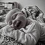 baby, black_and_white, blanket, child, content, cozy, cute, expression, face, fuzzy, happy, indoor, infant, lying_down, portrait, smiling, soft_texture, toddler, warm, wrapped