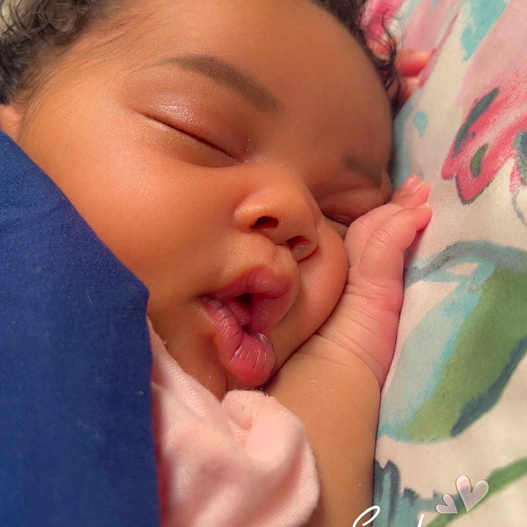Nayloni joined the competition — help win amazing prizes! baby, sleeping, face, blanket, pillow, hand, curly_hair, skin, peaceful, closeup, infant, cozy, soft_light, indoors, cute, portrait, child, rest, pink_clothing, colorful_background