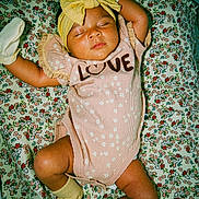 Keilani joined the competition — help win amazing prizes! baby, sleeping, headband, bow, pink_outfit, socks, floral_blanket, pattern, cute, infant, child, peaceful, resting, clothing, portrait, indoors, soft_lighting, cozy, yellow, adorable