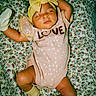 baby, sleeping, headband, bow, pink_outfit, socks, floral_blanket, pattern, cute, infant, child, peaceful, resting, clothing, portrait, indoors, soft_lighting, cozy, yellow, adorable