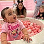 toddler, child, ball_pit, pink, shirt, minnie_mouse, dance, playground, indoor, happy, person, fun, toys, balls, baby, smiling, hand, face, blurred_background, casual_clothing