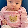 Mila is registered to the contest to win money with this photo: baby, infant, child, portrait, pink_clothing, onesie, bear_patch, sitting, close_up, face, eyes, hair, hand, legs, pajamas, bows_pattern, cute, indoor, lap, blanket