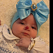Destini-Grace is registered to the contest to win money with this photo: accessory, baby, blue_bow, bracelet, calm, child, closeup, cute, embroidery, face, fashion, headband, indoors, infant, lying_down, nose_mark, polka_dot, portrait, soft_blanket, white_dress