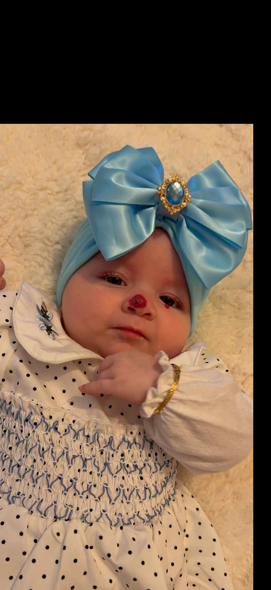 Destini-Grace is registered to the contest to win money with this photo: accessory, baby, blue_bow, bracelet, calm, child, closeup, cute, embroidery, face, fashion, headband, indoors, infant, lying_down, nose_mark, polka_dot, portrait, soft_blanket, white_dress
