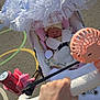 baby, stroller, hand, lace, canopy, outdoor, sunlight, toy, fan, energy_drink, drink_can, pavement, child, sleeping, person, clothing, pink, white, playground, accessory