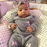 Genesis is registered to the contest to win money with this photo: baby, infant, child, headwrap, grey_outfit, pink_bow, knitted_blanket, indoor, cute, cozy, sitting, portrait, young_child, clothing, comfortable, soft_texture, relaxed, person, baby_clothes, fashion
