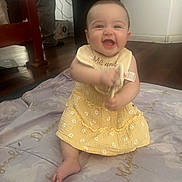 Adelina-Marie is registered to the contest to win money with this photo: baby, child, smiling, yellow_dress, sitting, indoor, blanket, happy, person, floor, wooden_floor, furniture, babygirl, cute, infant, clothing, portrait, face, expression, playful