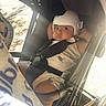 baby, helmet, stroller, child, infant, seatbelt, sunlight, outdoor, cute, face, expression, clothing, protection, toddler, sitting, shade, wheel, safety, person, portrait