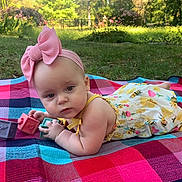 Ivy joined the competition — help win amazing prizes! baby, child, outdoor, blanket, toy, blocks, headband, pink_bow, romper, grass, park, nature, sunlight, curious, playing, infant, person, colorful, summer, cute