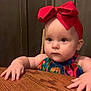 Ivy is registered to the contest to win money with this photo: baby, child, infant, red_bow, headband, colorful_clothing, table, wood, hands, curious, serious_face, indoor, portrait, person, cute, young, small_hands, sitting, closeup, furniture