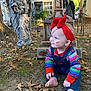 baby, child, face_paint, red_headband, colorful_clothing, denim_overalls, barefoot, fall_leaves, outdoor, yard, halloween, tombstone, angel_statue, skeleton_decoration, spooky, grass, tree, house, daylight, smiling