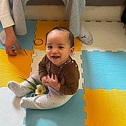 Raiatea participe au concours pour gagner de l'argent avec cette photo : adult_hand, baby, beaded_necklace, casual_clothing, child, colorful, cozy, floor, flower, foam_mat, footwear, happy, home, indoor, pajamas, person, playful, sitting, smiling, toy