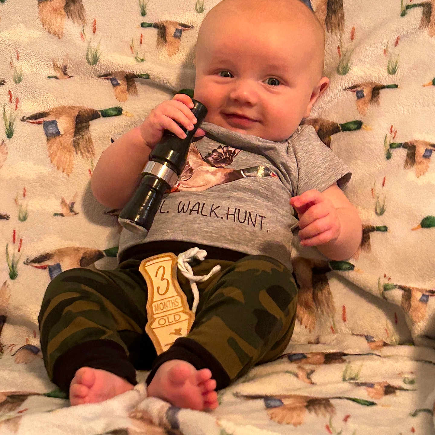 Tripp is registered to the contest to win money with this photo: baby, bodypart, bottle, clothing, electricaldevice, face, finger, furniture, hand, head, microphone, pants, person, photography, portrait, quilt, racket, shorts, sport, t_shirt