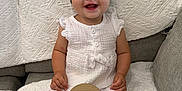 Avery is registered to the contest to win money with this photo: baby, infant, smiling, headband, bow, white_clothing, sitting, blanket, couch, texture, happy, child, indoors, cute, portrait, young_child, wooden_sign, eight_months, person, comfortable