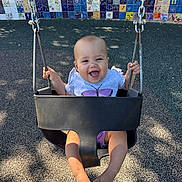 Avery is registered to the contest to win money with this photo: baby, swing, playground, child, smiling, happy, outdoor, sunlight, shadow, mosaic_wall, chains, feet, shirt, shorts, seat, play, infant, daylight, fun, park