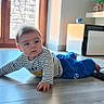 Leão a rejoint le concours — aidez-le/la à gagner de superbes lots ! baby, blue_pants, carpet, casual_clothing, child, crawling, curious, daylight, expression, floor, furniture, hands, home, indoor, modern_interior, natural_light, person, portrait, striped_shirt, wooden_window