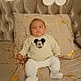 Leão participe au concours pour gagner de l'argent avec cette photo : baby, infant, bed, pillow, bedding, headboard, mickey_mouse, sweater, onesie, pajamas, portrait, sleepy, indoor, cozy, gold_pattern, tufted_headboard, blanket, sitting, face, feet