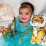 baby, child, smiling, turquoise_dress, headband, plush_tiger, golden_lamp, seven_months_sign, portrait, happy, indoors, cute, person, fabric, toy, celebration, face, infant, decor, texture