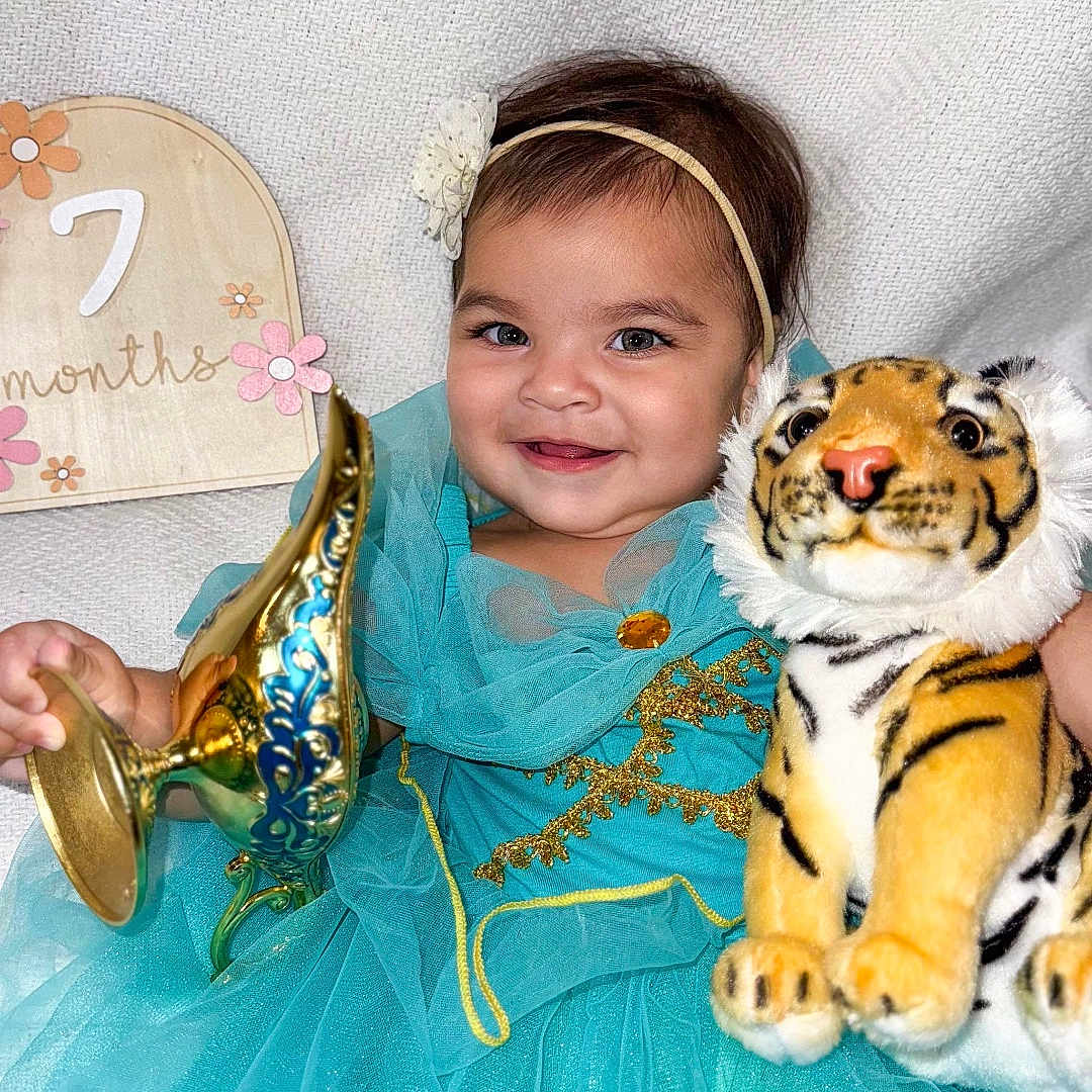Kamika joined the competition — help win amazing prizes! baby, celebration, child, cute, decor, fabric, face, golden_lamp, happy, headband, indoors, infant, person, plush_tiger, portrait, seven_months_sign, smiling, texture, toy, turquoise_dress