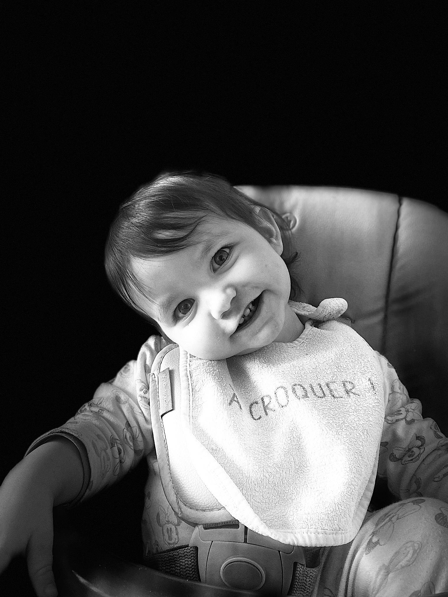 Kamélya participe au concours pour gagner de l'argent avec cette photo : arm, baby, baby_toddler_clothing, black, black_and_white, cheek, comfort, cool, darkness, flash_photography, happy, iris, joy, lip, monochrome, monochrome_photography, mouth, nose, person, sitting