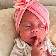 Maria-Valentina participe au concours pour gagner de l'argent avec cette photo : baby, child, closeup, cushion, cute, finger_on_lips, flower, headwear, indoors, infant, newborn, peaceful, pink_headwrap, portrait, resting, skin, sleepy, small_hands, soft_texture, white_clothing