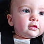 baby, close_up, face, child, infant, curious, expression, skin, eyes, lips, clothing, white_shirt, seatbelt, soft_light, portrait, young, head, cheeks, eyelashes, indoors